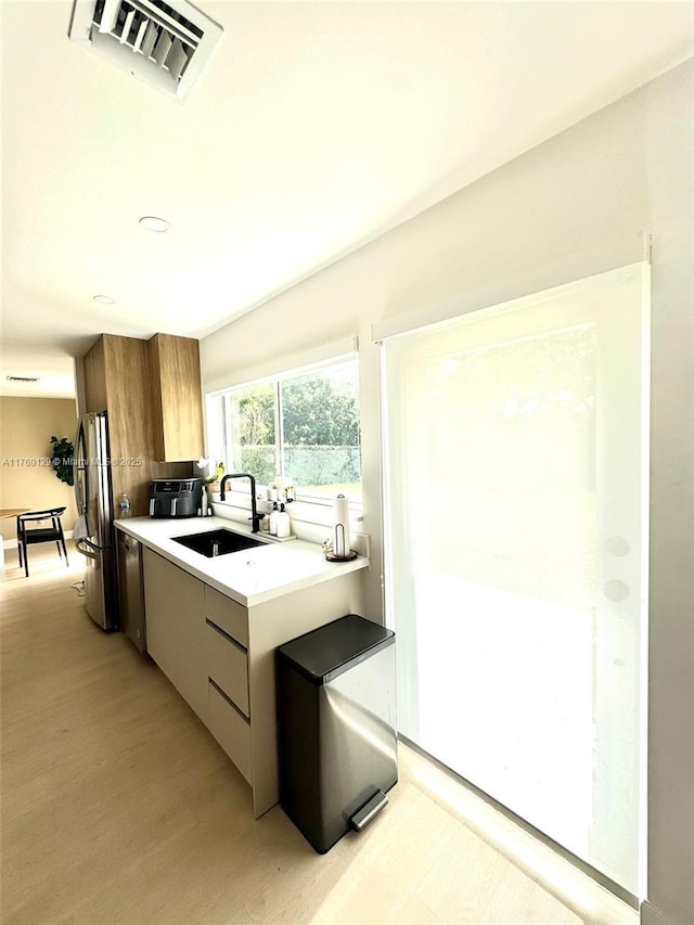 kitchen featuring visible vents, light countertops, stainless steel appliances, modern cabinets, and a sink