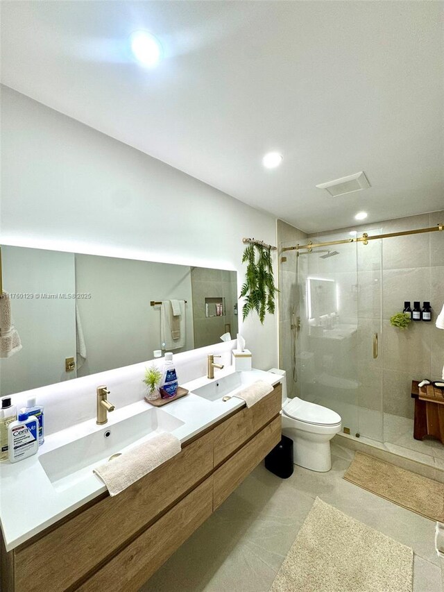full bath featuring visible vents, toilet, a sink, a shower stall, and double vanity