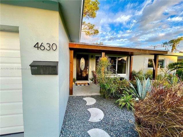 view of exterior entry with metal roof and stucco siding