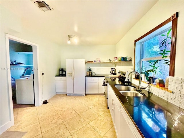 kitchen featuring dark countertops, visible vents, stainless steel electric stove, white fridge with ice dispenser, and a sink