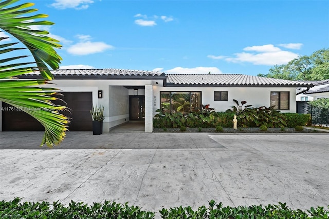 view of front of house with stucco siding, a tiled roof, concrete driveway, and a garage