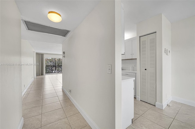 corridor featuring light tile patterned floors and baseboards