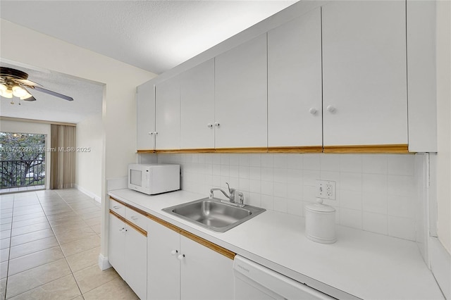 kitchen with white appliances, a sink, decorative backsplash, light countertops, and a textured ceiling