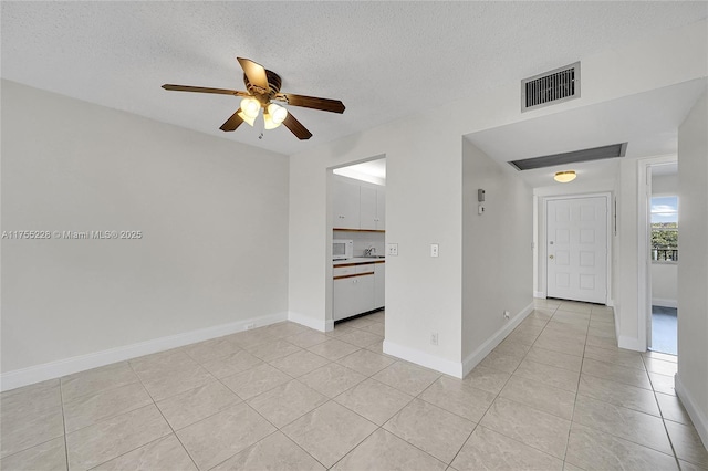 unfurnished room with light tile patterned floors, visible vents, a textured ceiling, and ceiling fan