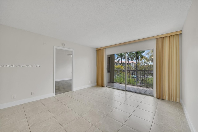 empty room featuring light tile patterned floors, baseboards, and a textured ceiling