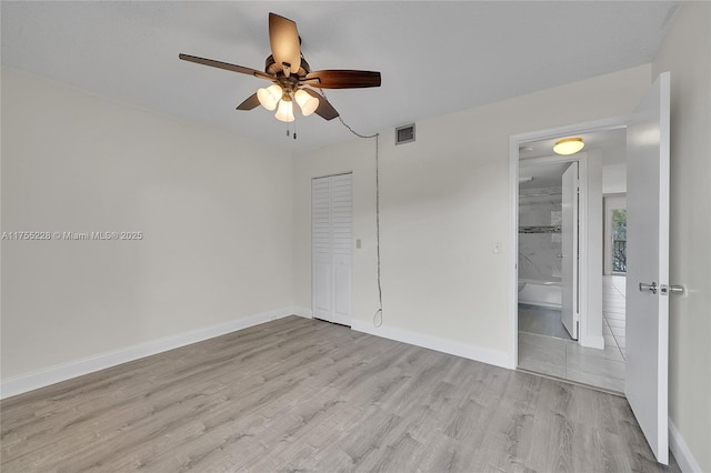 unfurnished bedroom featuring a closet, visible vents, baseboards, and wood finished floors