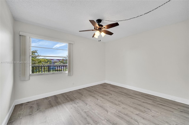 empty room with a textured ceiling, a ceiling fan, baseboards, and wood finished floors