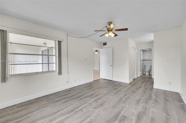 empty room featuring visible vents, baseboards, wood finished floors, a textured ceiling, and a ceiling fan