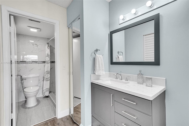 bathroom featuring vanity, toilet, wood finished floors, and a stall shower