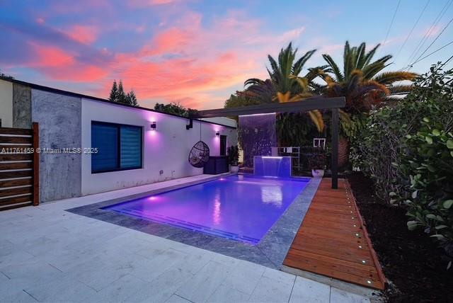 pool at dusk featuring an outdoor pool and a patio