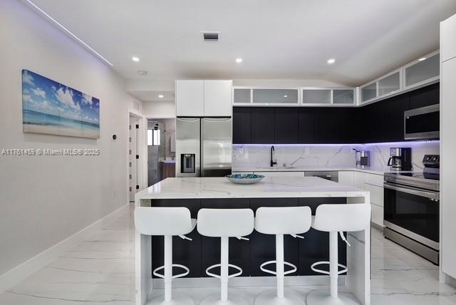 kitchen featuring a kitchen bar, marble finish floor, appliances with stainless steel finishes, and visible vents