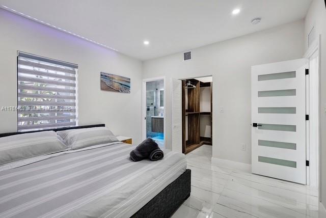 bedroom featuring visible vents, a walk in closet, marble finish floor, ensuite bathroom, and recessed lighting