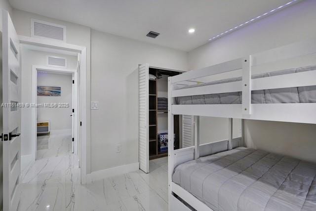 bedroom with a closet, visible vents, marble finish floor, and baseboards