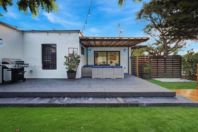 back of property featuring fence, stucco siding, a deck, outdoor lounge area, and a lawn