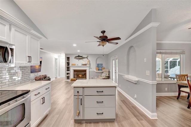 kitchen with light countertops, backsplash, light wood-style floors, and appliances with stainless steel finishes