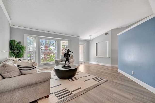 living area with wood finished floors, baseboards, visible vents, ornamental molding, and vaulted ceiling