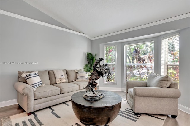 living room featuring crown molding, light wood-type flooring, baseboards, and vaulted ceiling