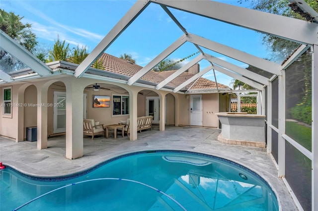 outdoor pool featuring glass enclosure, an outdoor hangout area, a ceiling fan, and a patio area