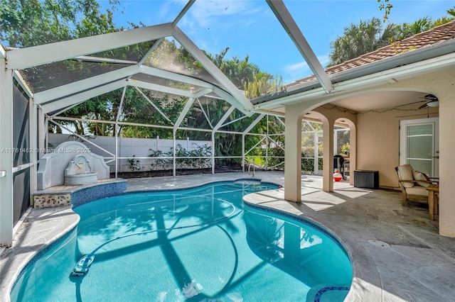 view of swimming pool featuring fence, glass enclosure, a fenced in pool, ceiling fan, and a patio area