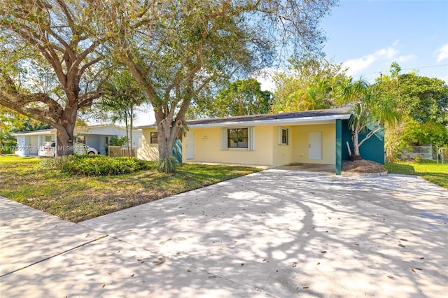 ranch-style house featuring stucco siding, an attached carport, concrete driveway, and a front yard