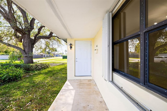 view of exterior entry featuring a lawn and stucco siding