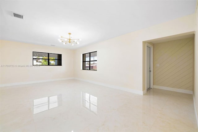 empty room with wooden walls, baseboards, visible vents, an inviting chandelier, and marble finish floor