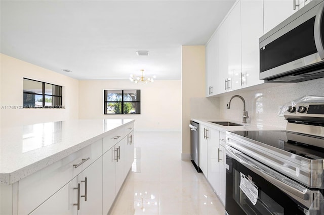 kitchen with visible vents, a sink, light stone counters, backsplash, and stainless steel appliances