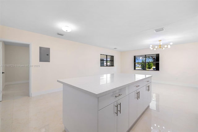 kitchen featuring visible vents, electric panel, a center island, white cabinets, and light countertops