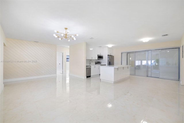 unfurnished living room featuring a notable chandelier, visible vents, baseboards, and a sink