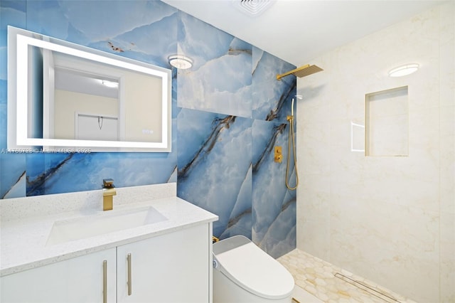 bathroom with visible vents, toilet, vanity, and a tile shower