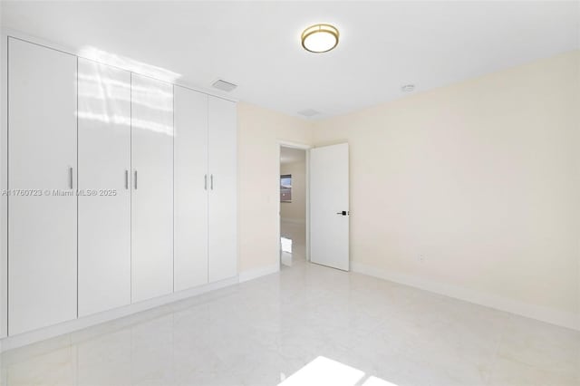 unfurnished bedroom featuring visible vents, baseboards, and a closet