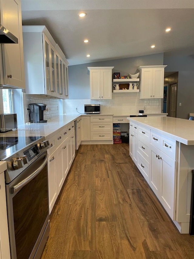 kitchen with dark wood-type flooring, light countertops, exhaust hood, white cabinets, and stainless steel appliances