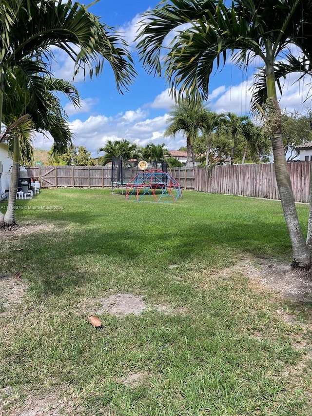 view of yard featuring a trampoline and a fenced backyard