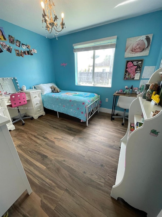 bedroom featuring baseboards, an inviting chandelier, and wood finished floors