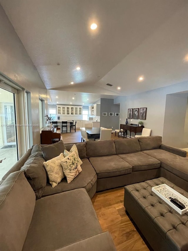 living room with vaulted ceiling, recessed lighting, light wood-type flooring, and visible vents