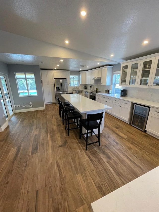 kitchen with wine cooler, a kitchen bar, dark wood-type flooring, and a sink