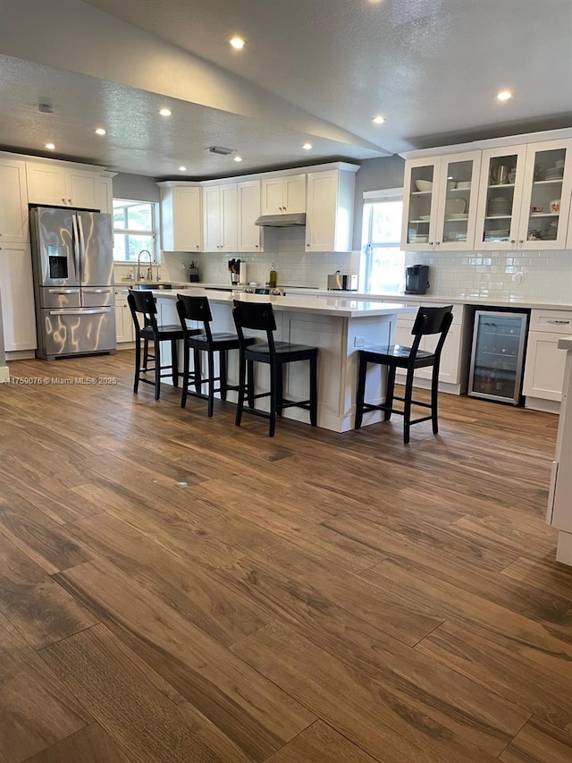 kitchen featuring beverage cooler, stainless steel fridge, and white cabinetry