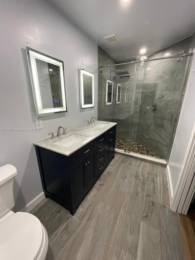 bathroom featuring toilet, wood finished floors, visible vents, and a sink