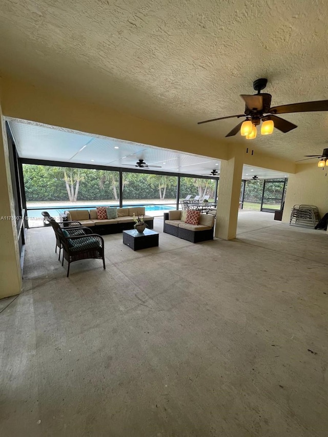 unfurnished living room with a textured ceiling, a ceiling fan, and a sunroom