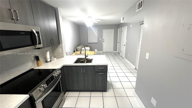 kitchen featuring visible vents, a peninsula, light tile patterned flooring, stainless steel appliances, and a sink