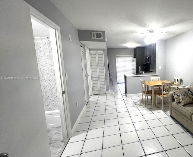 living area with visible vents, a textured ceiling, baseboards, and ceiling fan