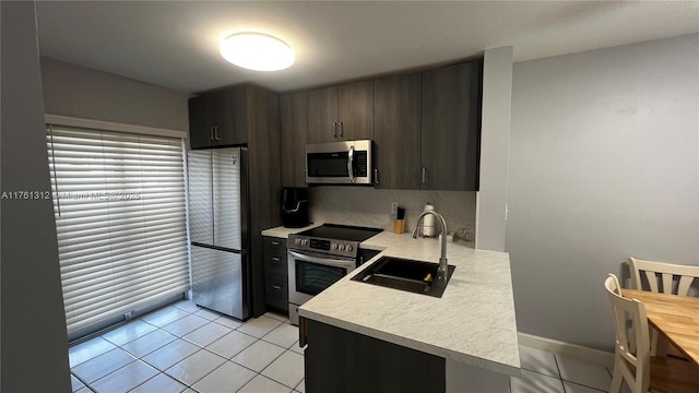 kitchen featuring light tile patterned floors, appliances with stainless steel finishes, light countertops, and a sink