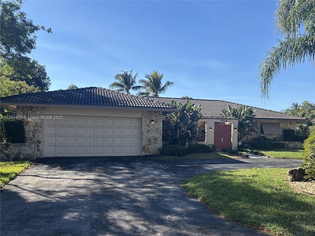 ranch-style home with an attached garage, a tiled roof, stucco siding, stone siding, and driveway