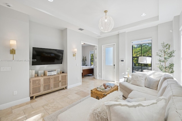 living room featuring visible vents, a raised ceiling, stone tile floors, recessed lighting, and baseboards