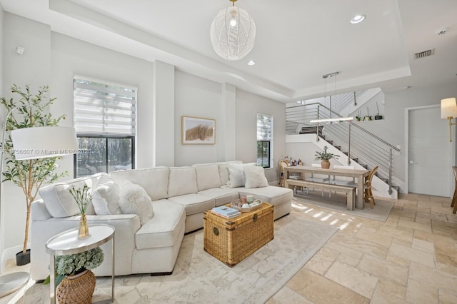 living area featuring visible vents, stairway, stone tile floors, recessed lighting, and a raised ceiling