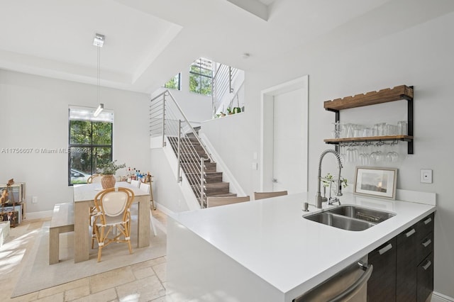 kitchen featuring stone tile floors, a sink, light countertops, dishwasher, and a raised ceiling