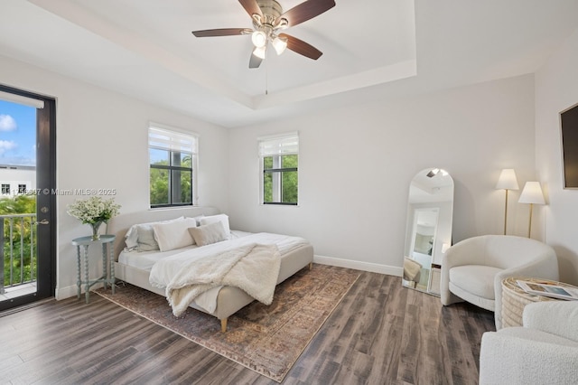 bedroom featuring a raised ceiling, baseboards, and wood finished floors