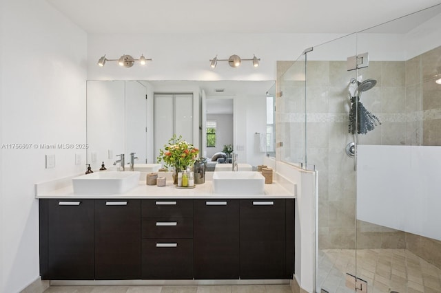 bathroom featuring double vanity, a stall shower, and a sink