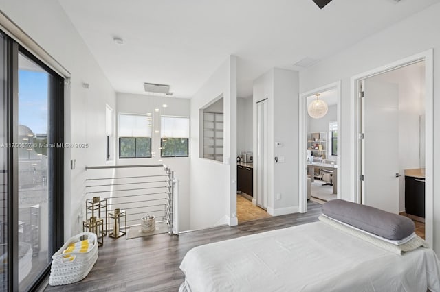 bedroom with connected bathroom, baseboards, wood finished floors, and access to exterior