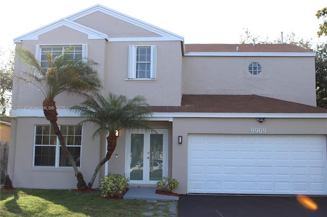 view of front facade featuring french doors, a garage, driveway, and stucco siding